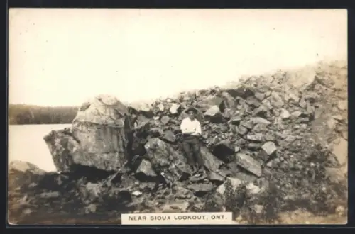 AK Sioux Lookout /Ont., Mann auf Felsen am See