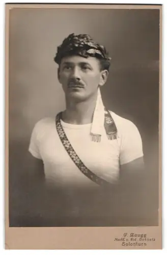 Fotografie F. Zaugg, Solothurn, Porträt eines Sportler im Turnerdress mit Siegerkranz auf dem Kopf, 1919