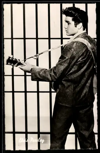 AK Musiker Elvis Presley mit Gitarre vor einem Gitter stehend