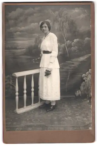 Fotografie unbekannter Fotograf und Ort, Elegante Dame in weissem Kleid vor gemalter Studiokulisse