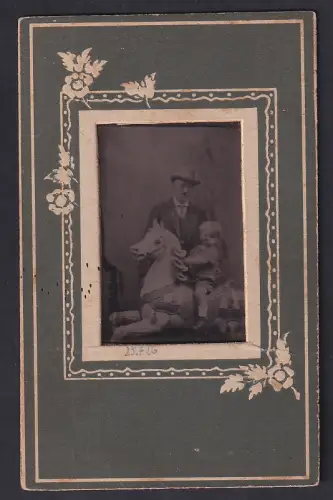 Fotografie Ferrotypie unbekannter Fotograf und Ort, Porträt eines Mannes mit Kind auf einem Schaukelpferd 1926