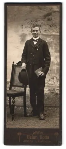 Fotografie Heinr. Bode, Alferde i. Hannover, Stehender Junge mit Hut und Buch