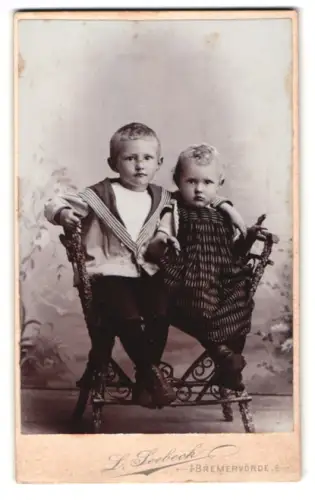 Fotografie L. Seebeck, Bremervörde, Zwei Kinder auf kunstvollem Stuhl