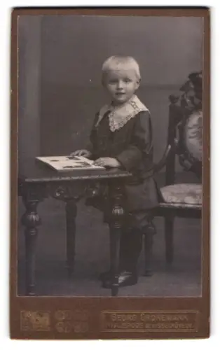 Fotografie Georg Gronemann, Walsrode, Kind an Tisch mit Buch