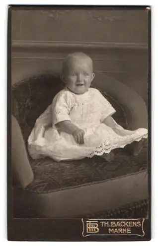 Fotografie Th. Backens, Marne, Kleinkind auf Sessel