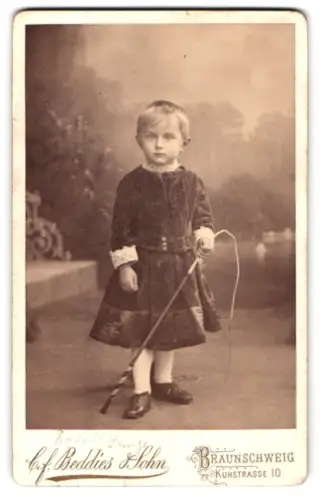 Fotografie C.F. Beddies Sohn, Braunschweig, Kuhstrasse 10, Kleinkind Rudolf Lunze mit Reitgerte