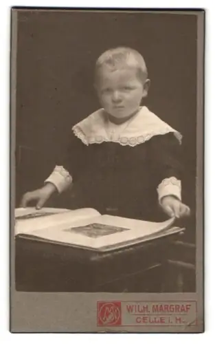 Fotografie Wilh. Margraf, Celle i. H., Kleiner Junge mit Buch