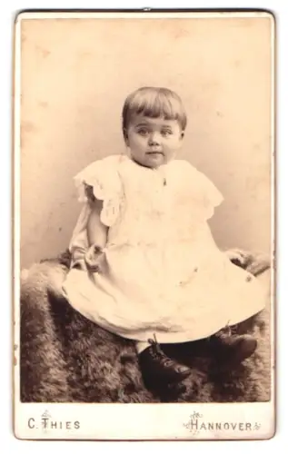 Fotografie C. Thies, Hannover, Höltystrasse 13, Kleinkind auf Fell sitzend