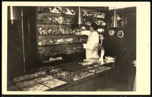Fotografie Juwelier-Geschäft, Verkäufer ordnet Waren in der Vitrine