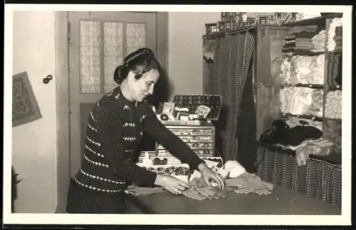 Fotografie Krueger, Berlin-Steglitz, Verkaufsdame in einem Tante Emma Laden legt Handschuhe zusammen