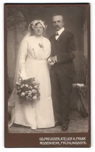 Fotografie Atelier K. Frank, Rosenheim, Frühlingsstr., Brautpaar mit Schleier und Blumenstrauss posiert zusammen