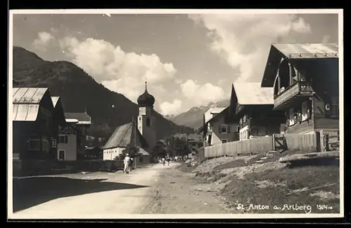 AK St. Anton a. Arlberg, Dorfstrasse mit Kirche und Bergpanorama