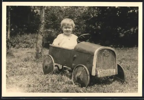 Fotografie Spielzeug-Auto, Kind im tretauto / Draisine sitzend