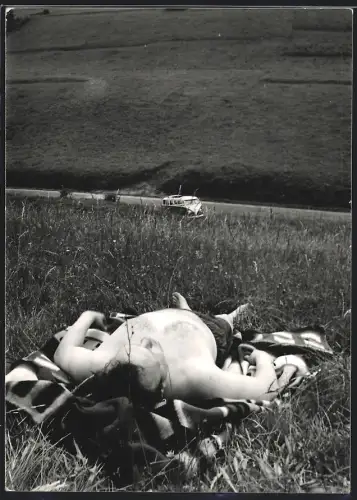 Fotografie beleibter Herr sonnt sich auf einer Almwiese, Auto Volkswagen VW Bulli steht unten am Feldweg