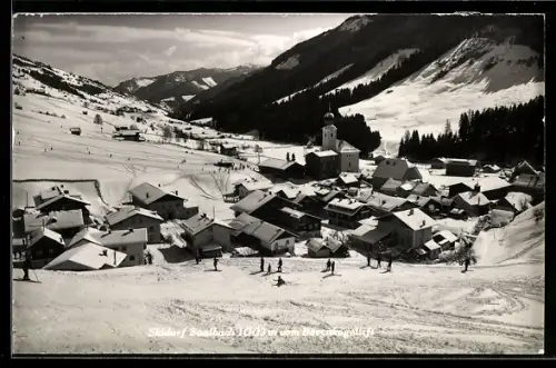AK Saalbach, Winterpanorama mit Kirche und Skifahrern