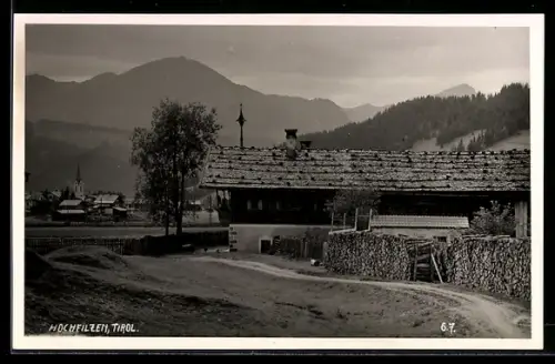 AK Hochfilzen /Tirol, Gehöft mit Brennholzstapel, Ortsblick und Bergpanorama