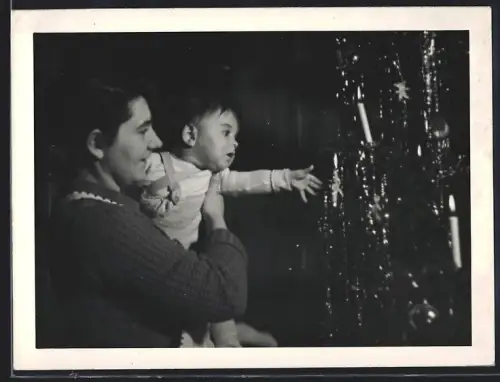 Fotografie Weihnachten, Baby greift nach dem Lametta im Weihnachtsbaum