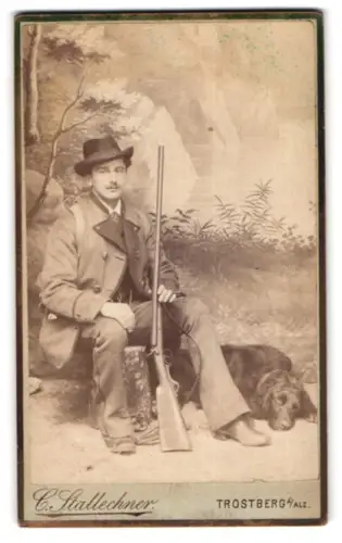 Fotografie C. Stallechner, Trostberg a. Alz, junger Jäger mit Flinte und Jagdhund vor einer Studiokulisse