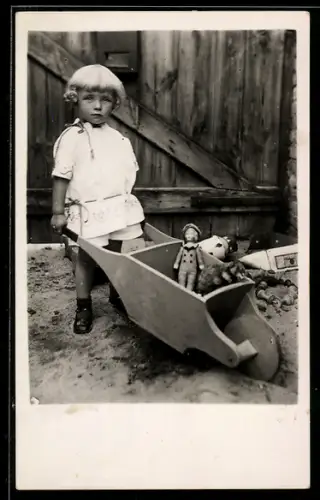 Foto-AK Kind mit Puppe in einer Schubkarre