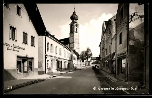 AK St. Georgen im Attergau, Geschäft von Josef Gossner, Strasse mit Kirche