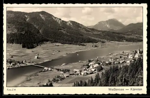 AK Weissensee /Kärnten, Panorama mit See, Dorf und Brücke