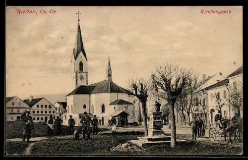 AK Riedau /Ob.-Oe., Kirchengasse, Panorama mit Kirche, Denkmal u. Versammlung