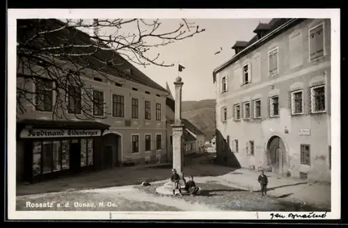 AK Rossatz a. d. Donau, Ortsplatz mit Brunnen und Häusern, Ladengeschäft Ferdinand Eidenberger