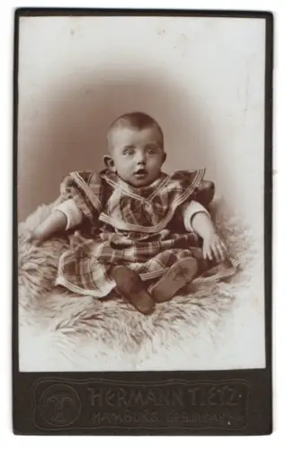 Fotografie Hermann Tietz, Hamburg, Gr. Burstah 12/14, Kleinkind auf einem Fell sitzend