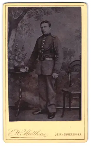 Fotografie E. E. Matthias, Seifhennersdorf, Soldat in Uniform mit Schützenschnur und Schirmmütze