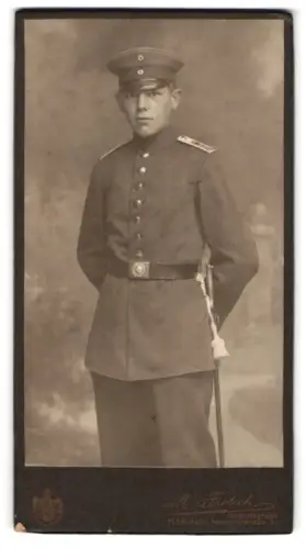 Fotografie M. Frölich, Flensburg, Norderhofenden 9, Soldat in Uniform mit Schirmmütze und Seitenwaffe