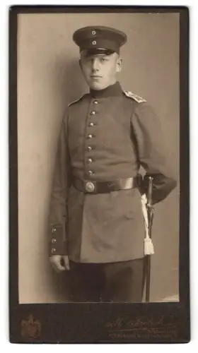 Fotografie M. Frölich, Flensburg, Norderhofenden 9, Soldat in Uniform mit Schirmmütze und Seitenwaffe, 1914