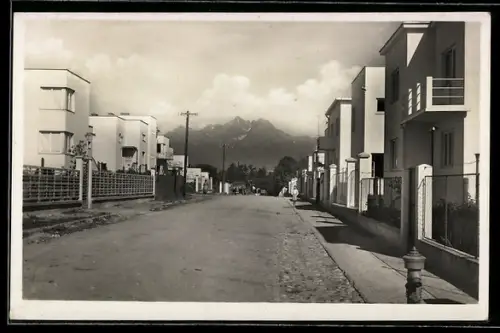 AK Kezmarok, Strasse mit Reihenhäusern und Bergen im Hintergrund