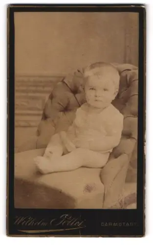 Fotografie Wilhelm Pöllot, Darmstadt, Portrait niedliches Kleinkind im weissen Hemd auf Sessel sitzend