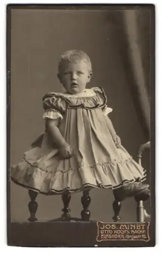 Fotografie Jos. Minet, Elmshorn, Panjestrasse 10, Kleinkind im gestreiften Kleid auf Stuhl