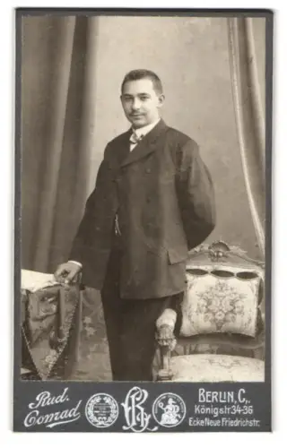 Fotografie Rud. Conrad, Berlin, Portrait charmant lächelnder Herr im Anzug