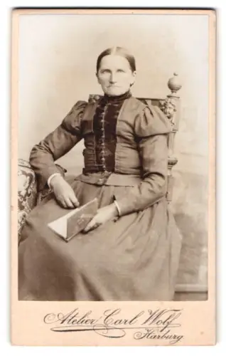 Fotografie Carl Wolf, Harburg, Frau mit Buch auf Stuhl sitzend