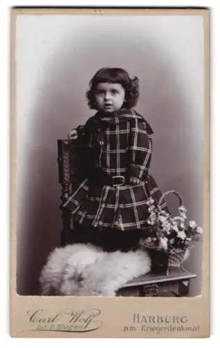 Fotografie Carl Wolf, Harburg, am Kriegerdenkmal, Kind in kariertem Kleid auf einem Stuhl stehend