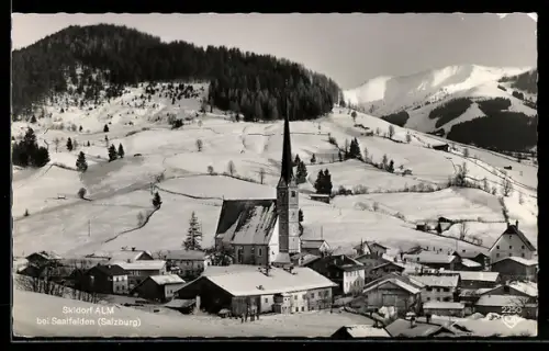 AK Alm bei Saalfelden, Dorf im Winter mit Kirche und Bergpanorama
