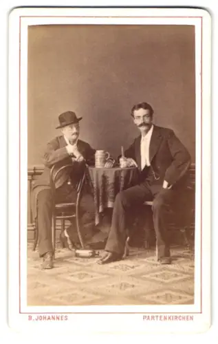 2 Fotografien B. Johannes, Partenkirchen, Portraits von zwei Zechbrüdern an einem Tisch, mit und ohne Hut