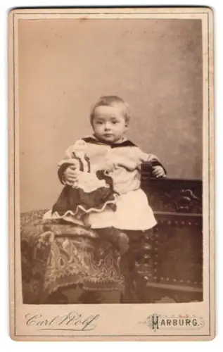 Fotografie Carl Wolf, Harburg, Kleinkind mit einer Spielzeugpuppe