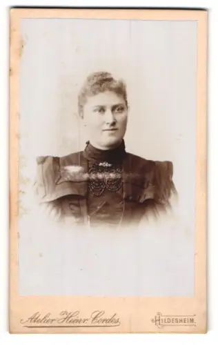 Fotografie Heinr. Cordes, Hildesheim, Portrait junge Dame im bestickten Kleid mit Kragenbrosche
