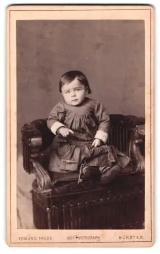 Fotografie Edmund Frede, Münster, Neubrückenstr. Nr. 6, Porträt eines kleinen Kindes auf Sessel