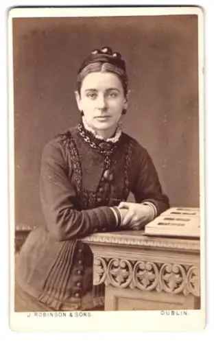 Fotografie J. Robinson & Sons, Dublin, Grafton St 65, Frau im eleganten Kleid an einem Tisch