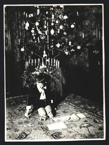 Fotografie Weihnachten, Knabe mit Spielzeug unterm Weihnachtsbaum