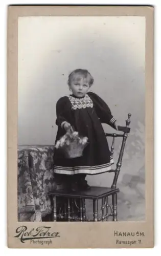 Fotografie Rob. Fetzer, Hanau a. M., Ramsaystr. 11, Kind mit Korb auf Stuhl