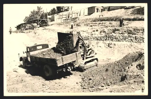 Fotografie Baumaschine Raupenlader / Kettenlader belädt Lastwagen, LKW-Pritsche mit Erdaushub