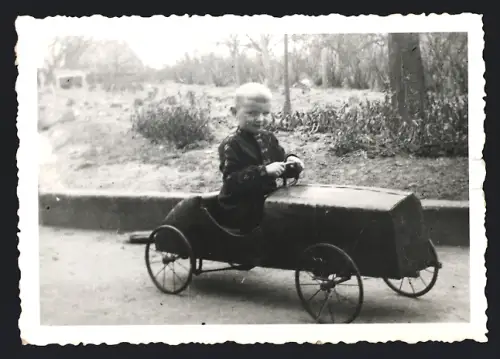 Fotografie Knabe im Tretauto / Draisine sitzend