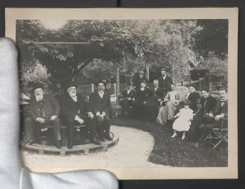 Fotografie unbekannter Fotograf und Ort, Gruppe sitzt gemütlich zusammen im Garten