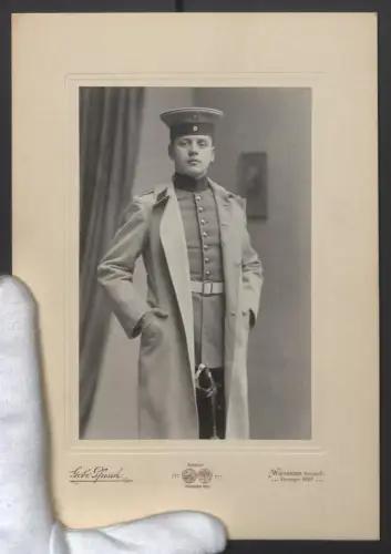 Fotografie Gebr. Pfusch, Wiesbaden, Rheinstr. 21, Soldat in Uniform mit Mantel