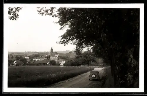 Foto-AK Lambrechten /O. Ö., Ortsansicht mit Kirche, baumgesäumte Landstrasse mit Auto